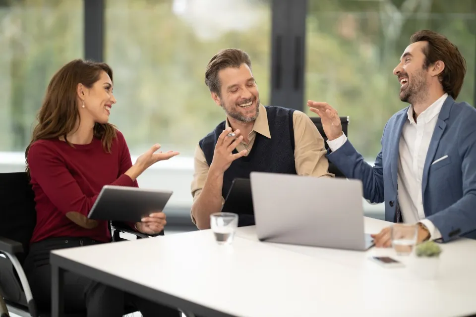 A woman with a tablet talking with two male colleagues at a meeting table