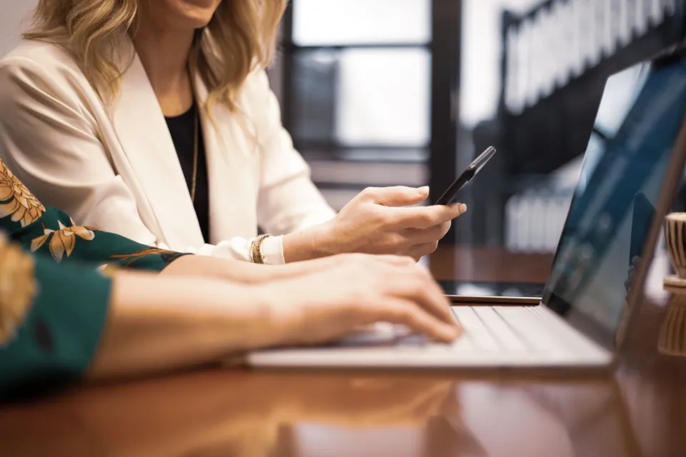 Two women working on laptops at a wooden table